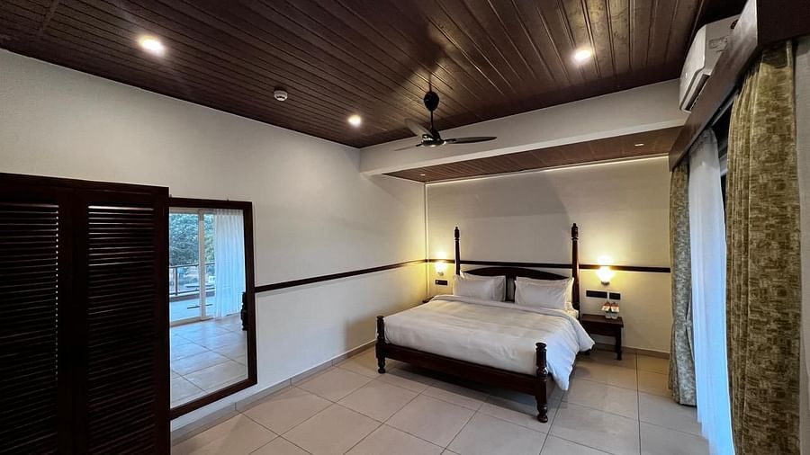 Grand Suite room with a comfortable bed, wooden furniture, and large window at Mastiff Grand La Villae Resort, Lonavala